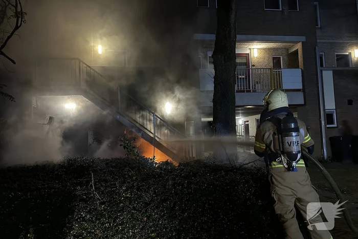Brandweer blust brandende container onder trap