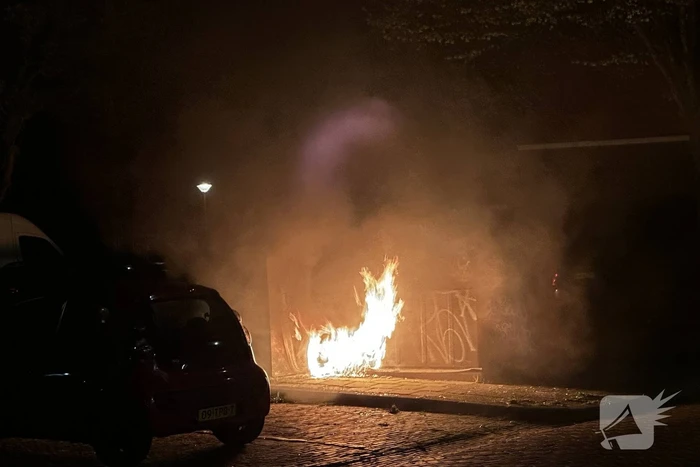 Brandweer blust brandend afval naast container
