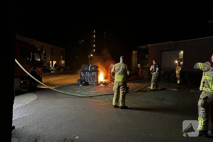 Brandweer blust brandend afval naast container