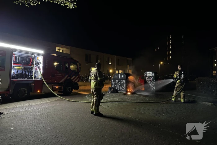 Brandweer blust brandend afval naast container