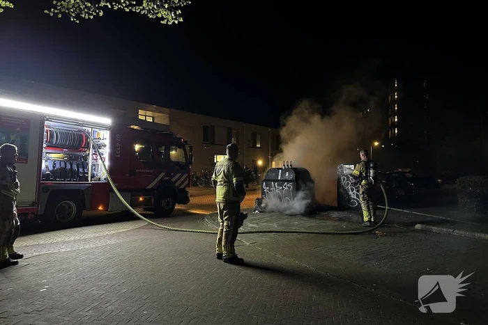 Brandweer blust brandend afval naast container
