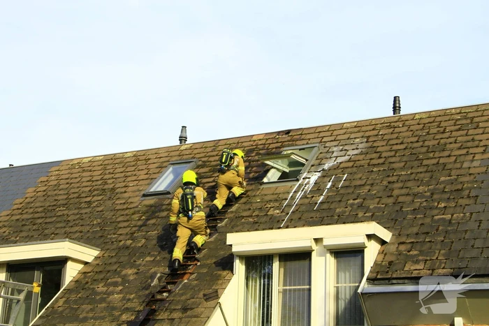 Brandweer breekt dak open om brand te bestrijden