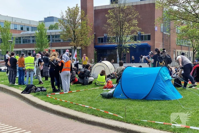 Studenten in tenten op grasveld bij UvA