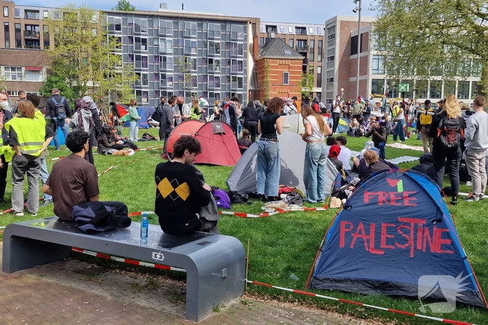 Studenten in tenten op grasveld bij UvA