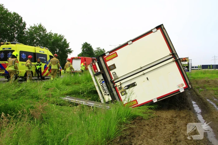 Vrachtwagen op zijn kant in sloot