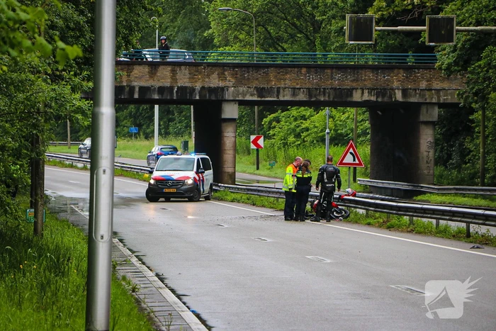 Motorrijder hard onderuit door water onder viaduct
