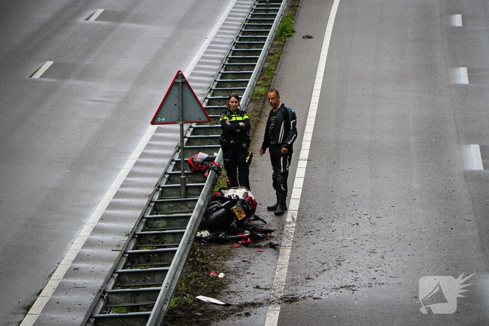 Motorrijder hard onderuit door water onder viaduct