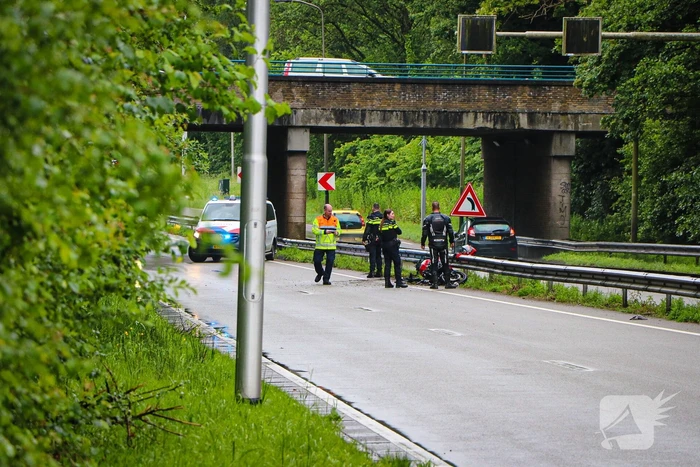Motorrijder hard onderuit door water onder viaduct
