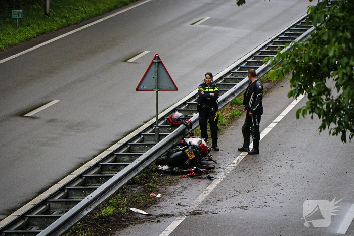Motorrijder hard onderuit door water onder viaduct