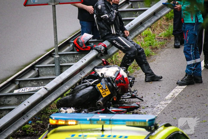 Motorrijder hard onderuit door water onder viaduct
