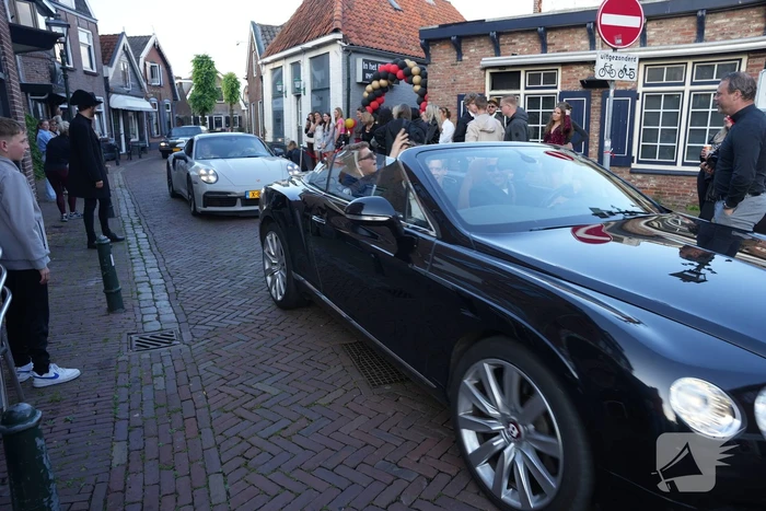 Leerlingen komen in bijzondere auto's aan bij examenfeest