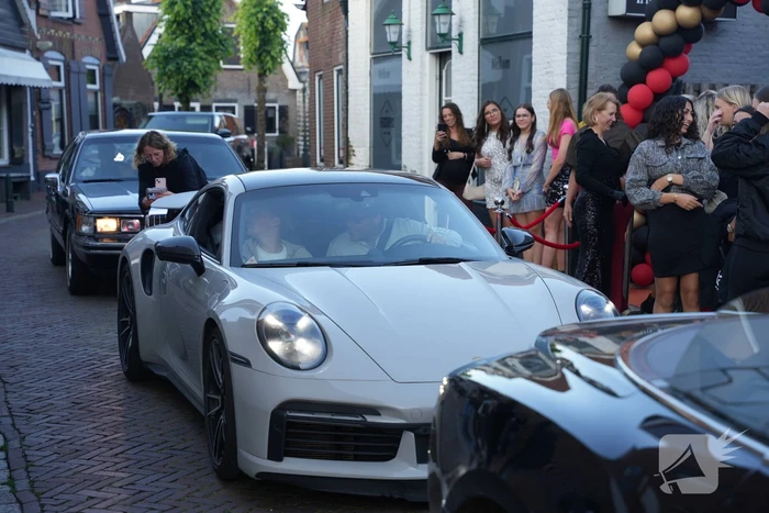 Leerlingen komen in bijzondere auto's aan bij examenfeest