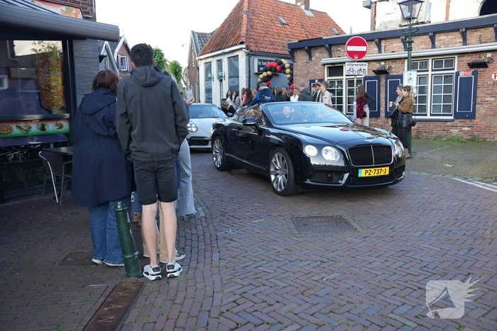 Leerlingen komen in bijzondere auto's aan bij examenfeest