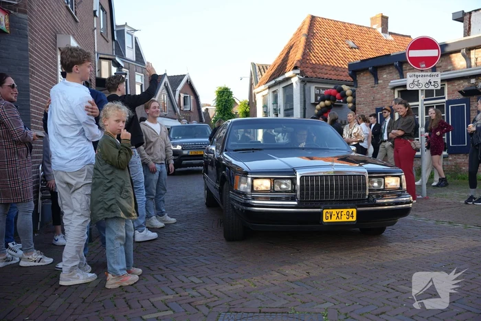 Leerlingen komen in bijzondere auto's aan bij examenfeest