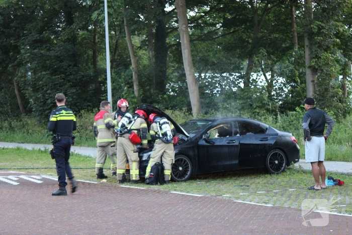 Brandweer blust brand in geparkeerde auto