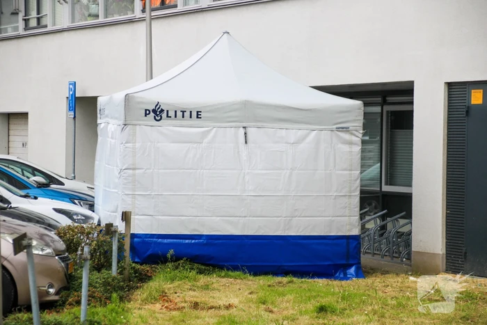 Forensisch onderzoek op parkeerplaats naast flatgebouw