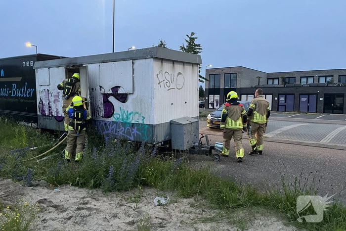 Brandweer blust in brand gestoken bouwkeet vol rommel
