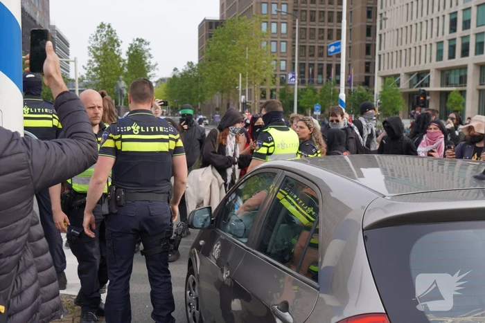 Demonstranten trekken persoon van scooter en slaan op auto's