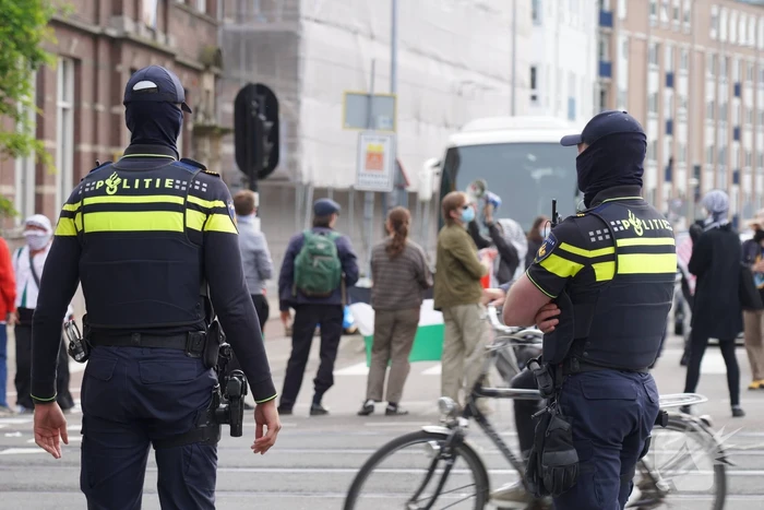 Demonstranten trekken persoon van scooter en slaan op auto's