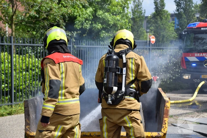 Brandweer blust brand in bouwcontainer