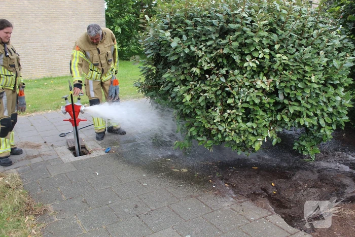 Brandweer blust buitenbrand met water uit brandkraan