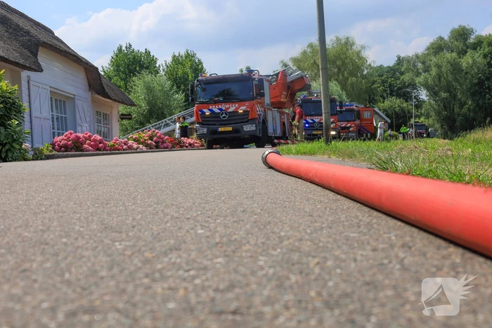 Brandweer blust brand in rietenkap van woning