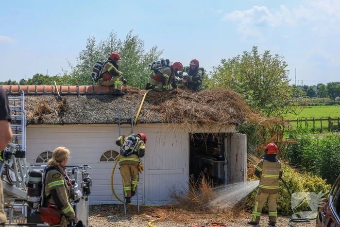 Brandweer blust brand in rietenkap van woning