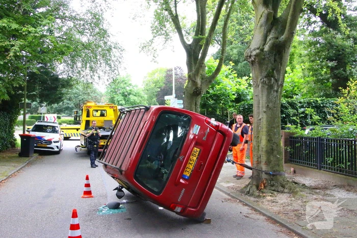Auto belandt op zijkant na botsing tegen boom