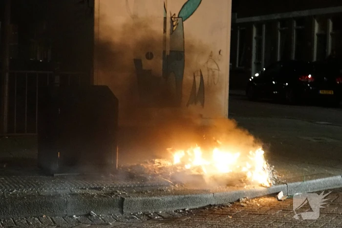 Brandweer blust brand naast afvalcontainer