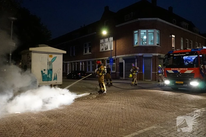 Brandweer blust brand naast afvalcontainer