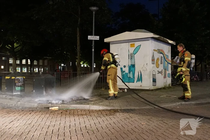 Brandweer blust brand naast afvalcontainer