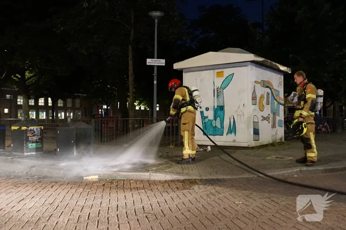 Brandweer blust brand naast afvalcontainer