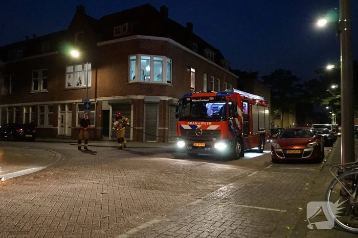 Brandweer blust brand naast afvalcontainer