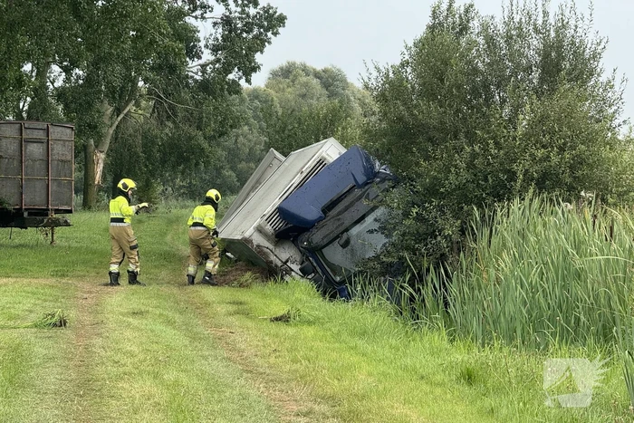 Vrachtwagen belandt in sloot naast snelweg, chauffeur ongedeerd