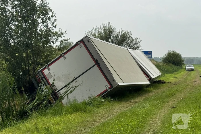 Vrachtwagen belandt in sloot naast snelweg, chauffeur ongedeerd