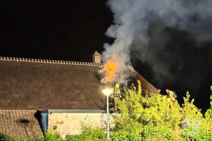 Vlammen slaan uit rietendak van woning