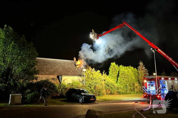 Vlammen slaan uit rietendak van woning