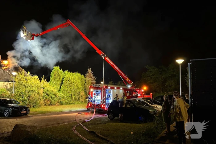 Vlammen slaan uit rietendak van woning