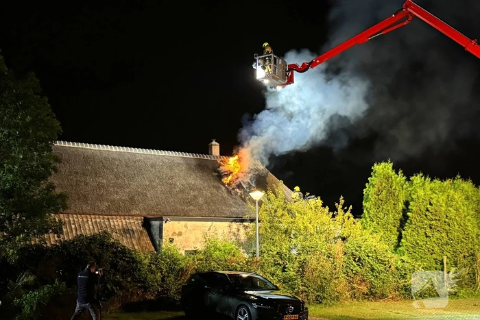 Vlammen slaan uit rietendak van woning