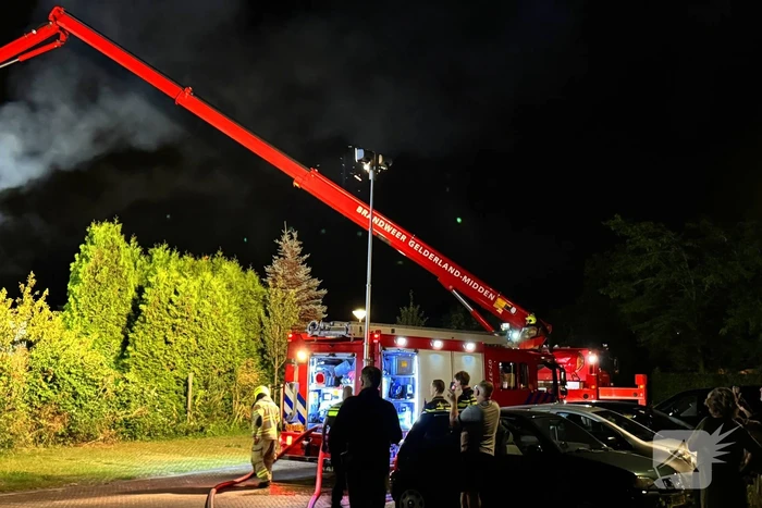 Vlammen slaan uit rietendak van woning