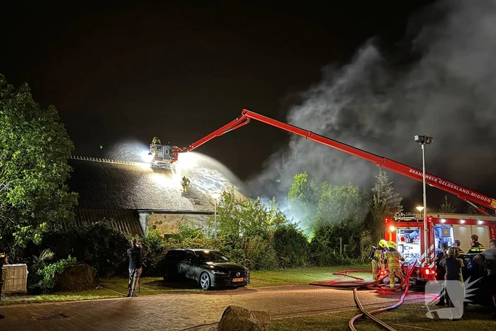 Vlammen slaan uit rietendak van woning