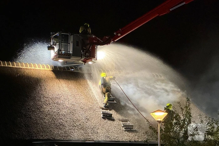Vlammen slaan uit rietendak van woning