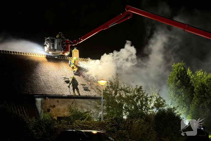 Vlammen slaan uit rietendak van woning