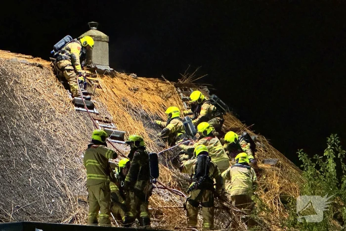 Vlammen slaan uit rietendak van woning