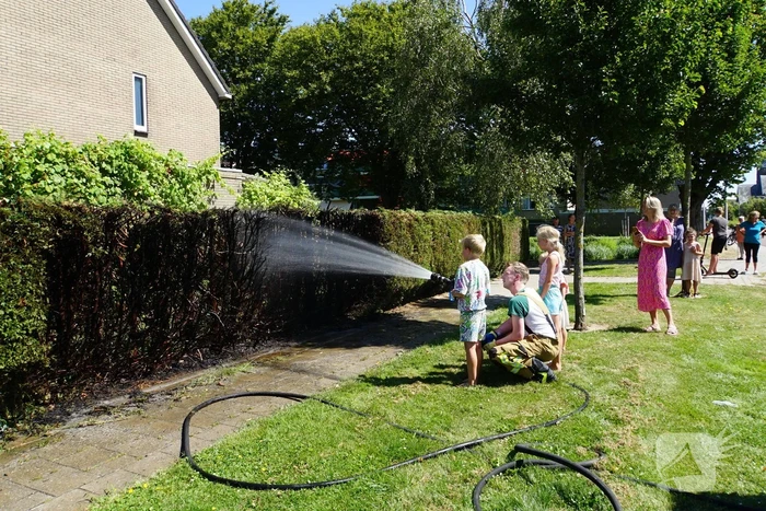 Kinderen blussen met brandweer brandende coniferenhaag