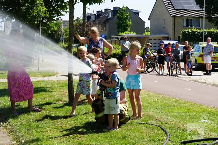 Kinderen blussen met brandweer brandende coniferenhaag