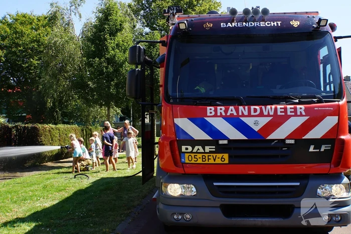 Kinderen blussen met brandweer brandende coniferenhaag