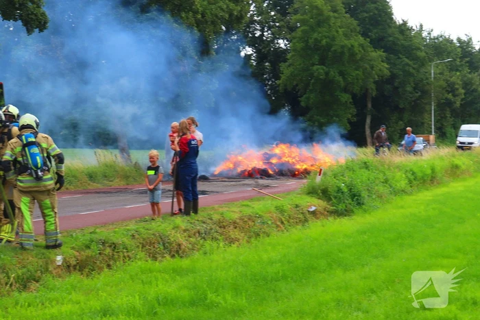 Brandweer blust brandend stro op aanhanger