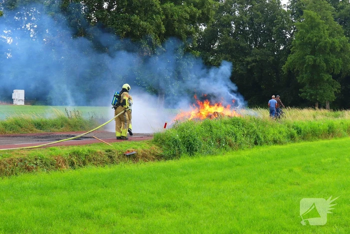 Brandweer blust brandend stro op aanhanger