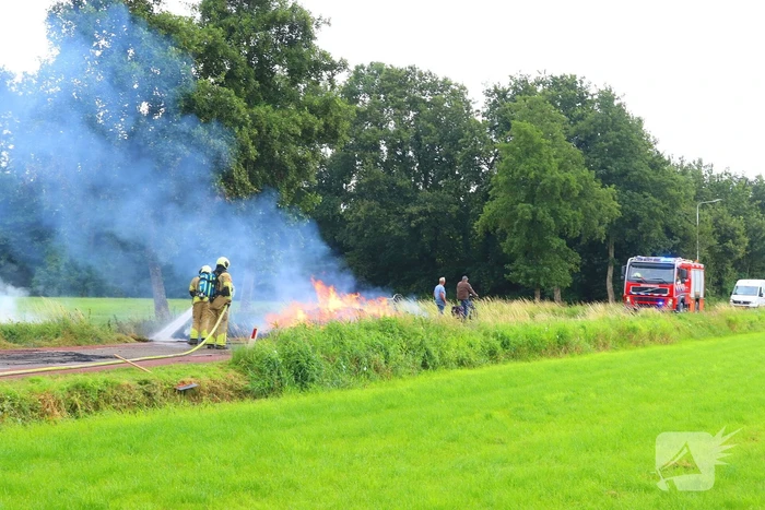 Brandweer blust brandend stro op aanhanger